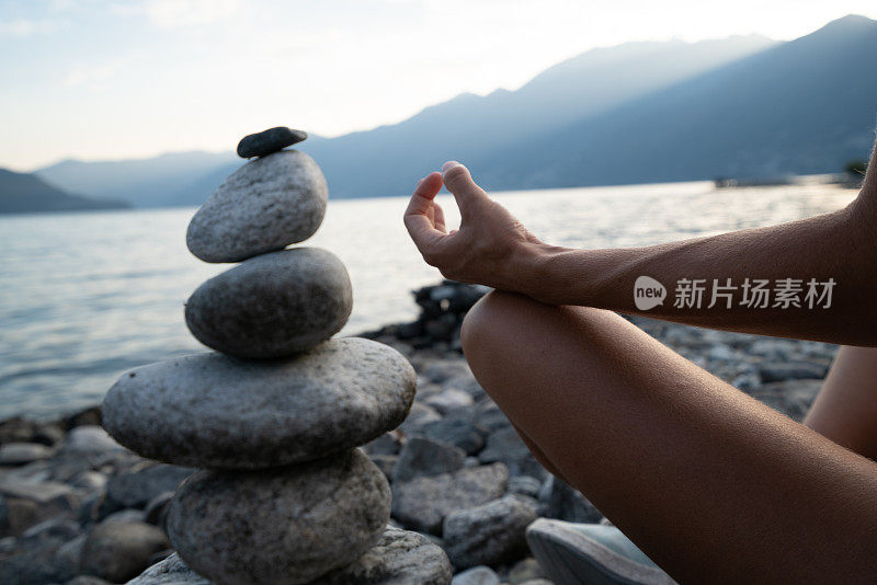 日落时分在湖边的stack rock附近练习瑜伽和冥想的人的细节